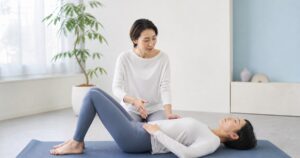 マットピラティスで呼吸を確認する女性と指導者