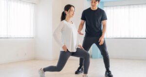 運動前に動的ランジを行う女性と指導者