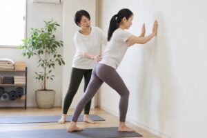 壁を使ったふくらはぎのストレッチを行う女性
