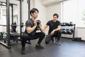 ゴブレットスクワットを個別指導で行う男性