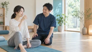床のマット上で整体後に少量の水を飲み担当者と体調を確認する写真